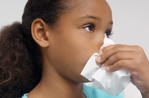 Young girl holding a tissue to her nose